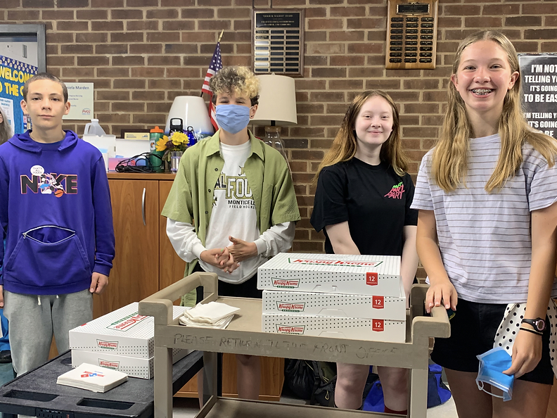 Four children posing with Krispy Kreme donuts at a school